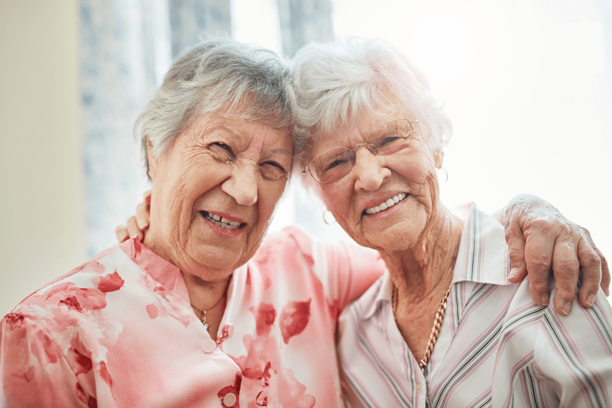 Friends, senior women and retirement home with hug or happy and fun. Pensioner, portrait and smile or confident in bonding to relax on break at old age house for wellbeing, wellness and health